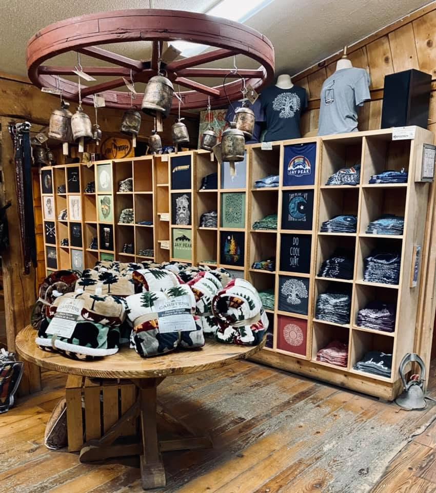 Jay Peak shirts and patterned blankets beneath a wagon-wheel fixture inside the store